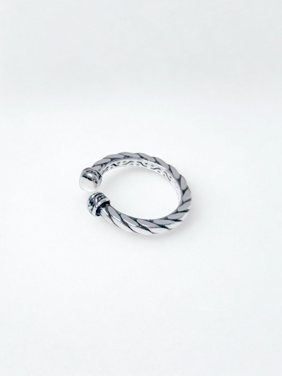 Silver ring with a twisted design on a white background