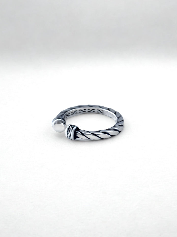 Silver ring with a textured design on a white background